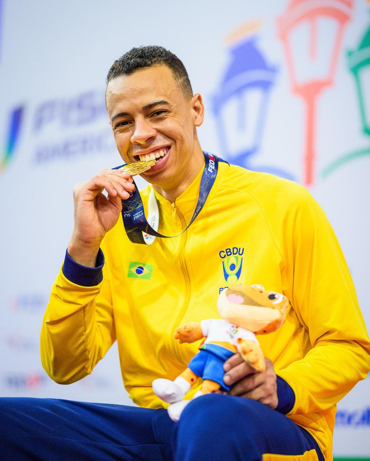 Luiz Augusto mordendo a medalha de ouro conquistada em Lima
